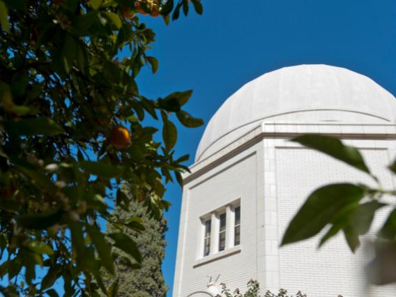 looking up at a white dome top of a UA building under a clear blue sky